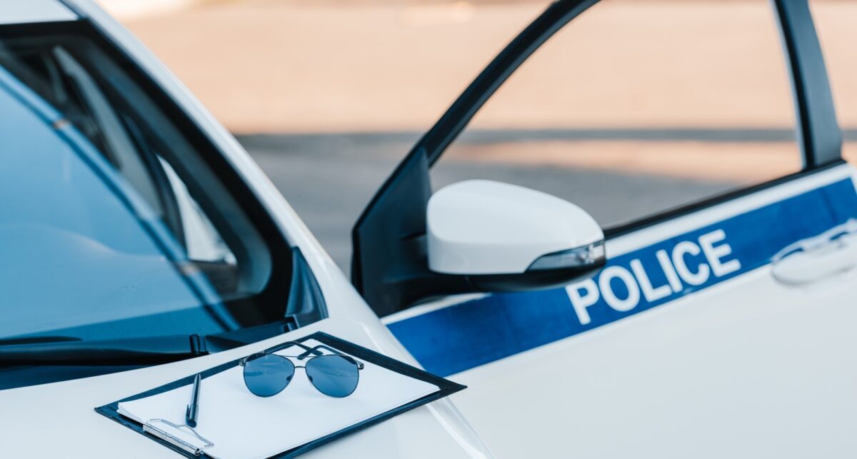blank clipboard with sunglasses on automobile with flasher and lettering police at city street
